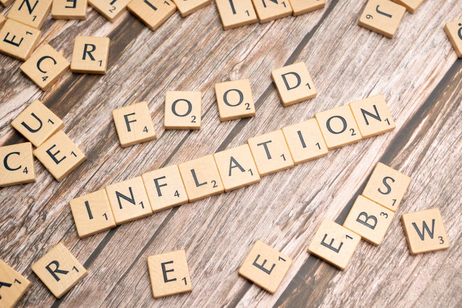 A close-up image of wooden Scrabble tiles arranged on a rustic wooden surface, spelling out the words 'COVID,' 'FAKE,' and 'INFLATION.' The tiles are light-colored with black letterings and point valu